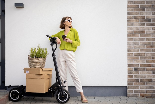 Woman standing near scooter with parcels and flowerpot