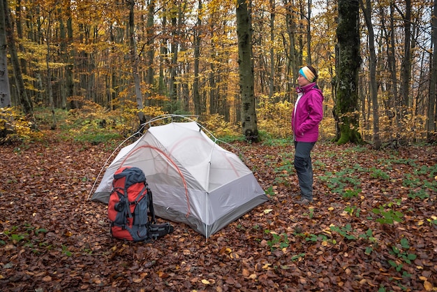 Woman standing near the tent in the forest