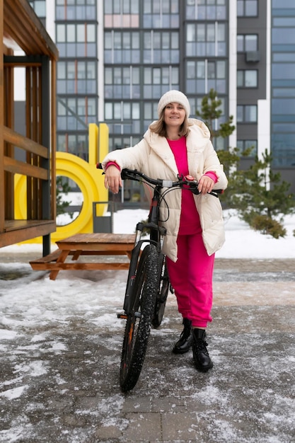 写真 雪の中の自転車の隣に立っている女性