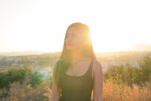 写真 夕暮れの空に照らされた畑に立っている女性