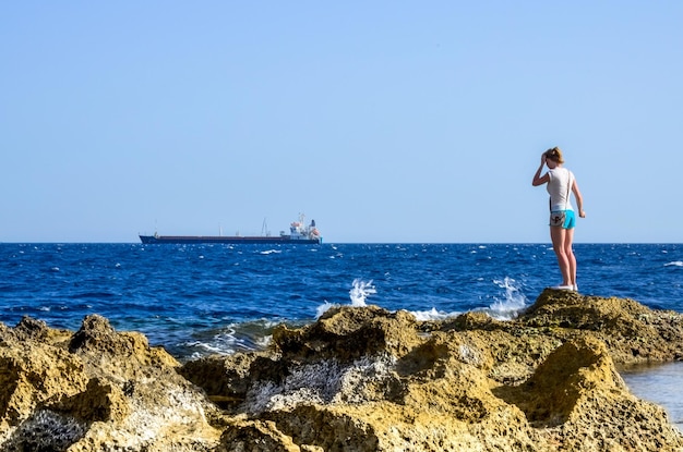 Фото Женщина, стоящая на скале у моря