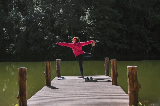 Foto donna in piedi sul molo vicino al lago