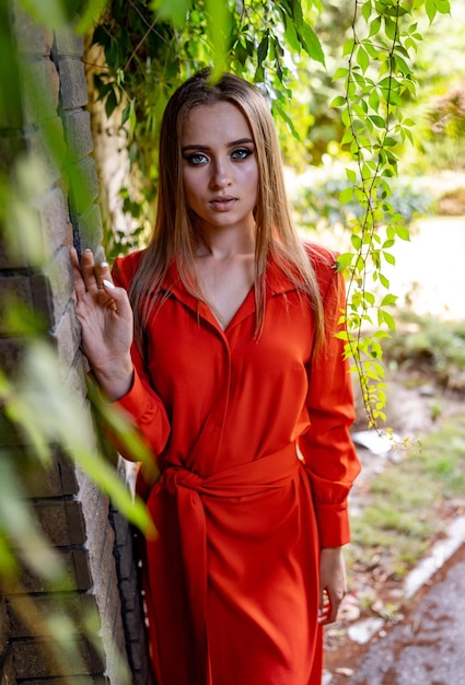 Woman standing next to red dress by brick wall a woman wearing a red dress stands confidently next to a brick wall