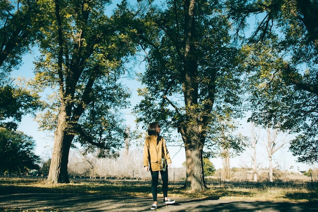 Woman standing on road against trees