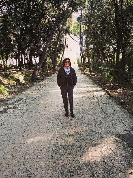 Foto donna in piedi sulla strada in mezzo agli alberi