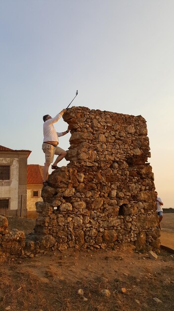 Woman standing on rock against clear sky