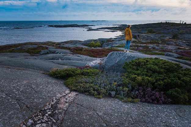 Foto donna in piedi su una roccia sulla spiaggia contro il cielo