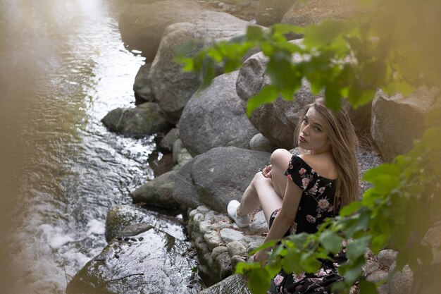 Foto donna in piedi su una roccia vicino all'acqua