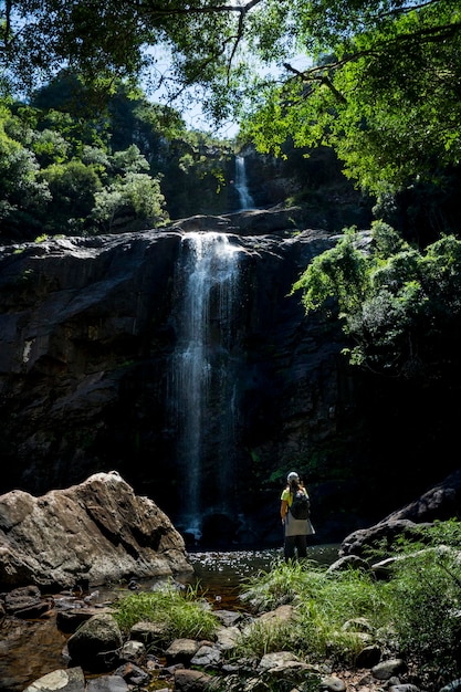 Woman standing on a rock looking at a waterfall adventure tourism concept