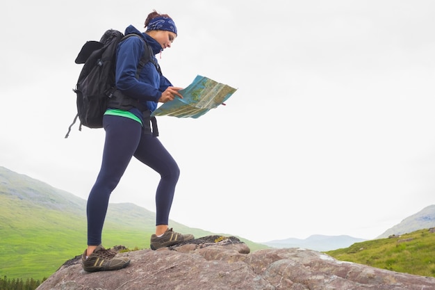 女性は地図を読んでいる岩に立っている