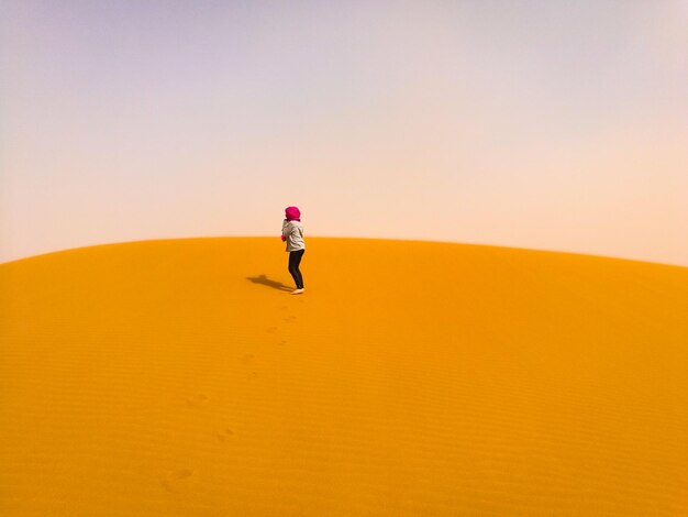 Photo woman standing on sand dune against sky at desert