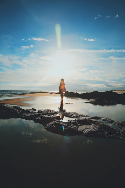 Woman standing in sea against sky