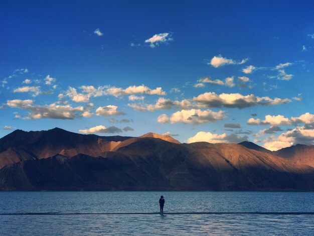 Woman standing in sea against sky