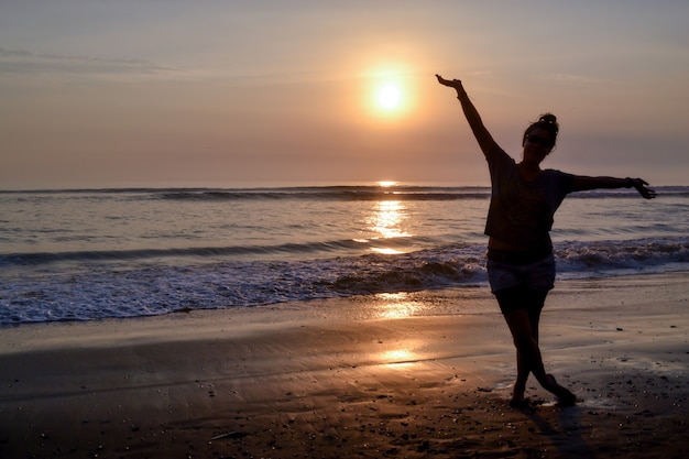 Woman standing on the shore of a beach at sunset