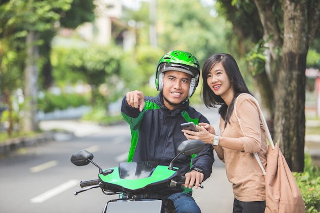 Woman standing on sidewalk talking and ordering motorcycle taxi