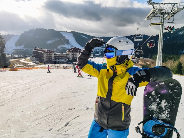 Woman standing at ski resort hill with snowboard