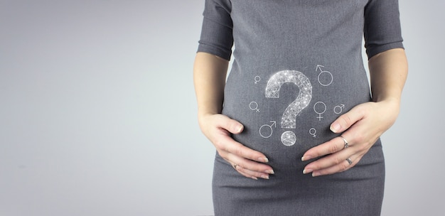 Woman standing and touching with hands her big belly with hologram question mark.