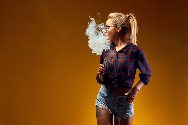 Photo woman standing and vaping in studio