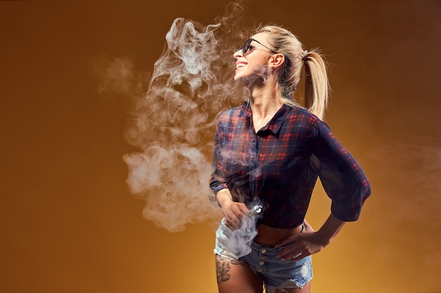 Photo woman standing and vaping in studio