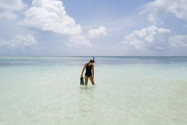 Woman standing in the water wearing wetsuit holding snorkeling equipment