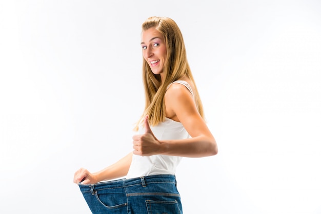 Photo woman standing and wearing a too big pants after loosing weight