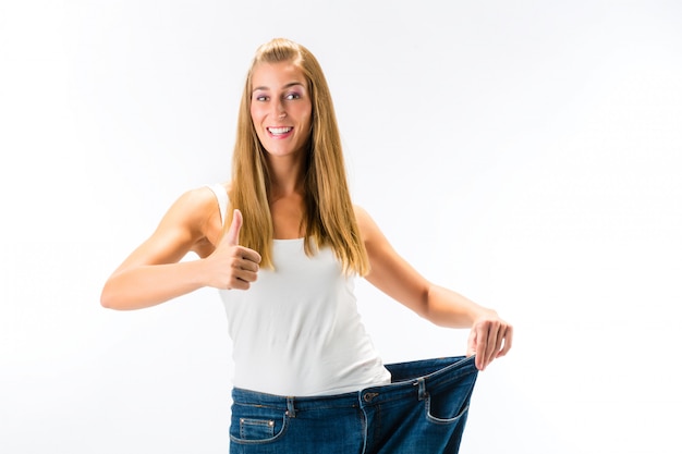 Woman standing and wearing a too big pants after loosing weight