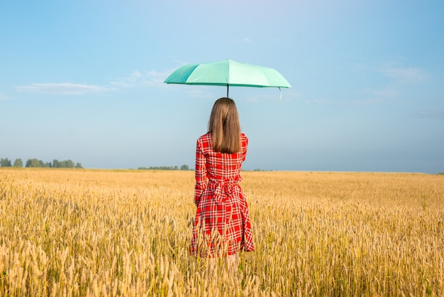 Woman standing on a wheat field with an umbrella