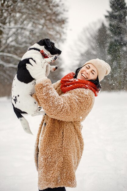 Woman standing at winter park and holding a black dog