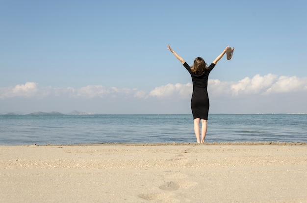 Женщина, стоя с вытянутыми руками на пляже в море