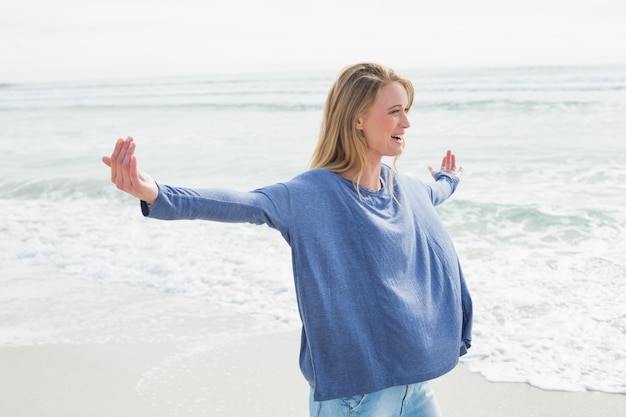 Женщина, стоя с вытянутыми руками на пляже