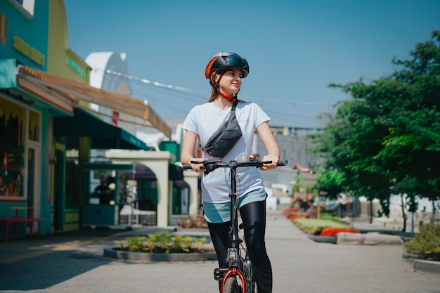 woman standing with a bicycle wearing a waistbag and sportswear at the park