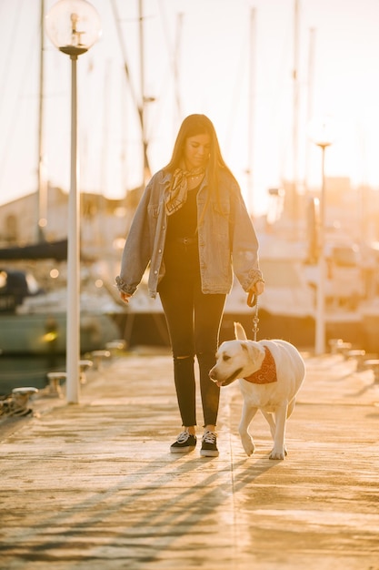 夕暮れの港で犬と立っている女性