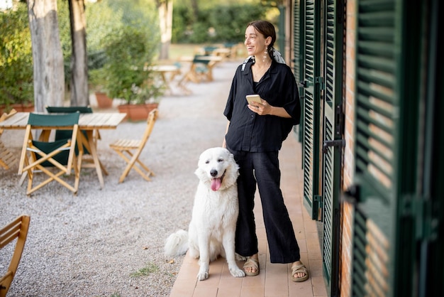 Donna in piedi con il cane e distoglie lo sguardo vicino all'ingresso della camera d'albergo