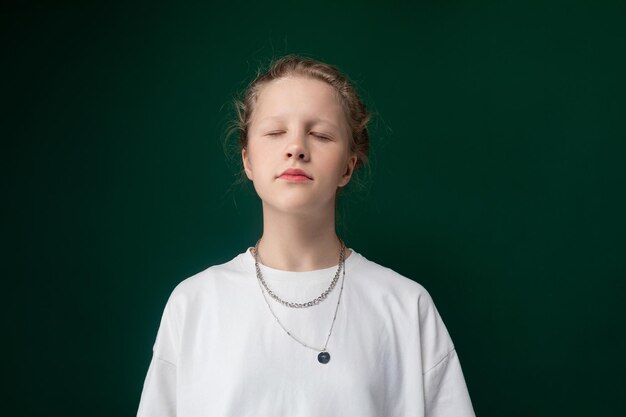 Woman standing with eyes closed in front of green background