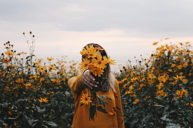 woman standing on yellow flowering plants on field