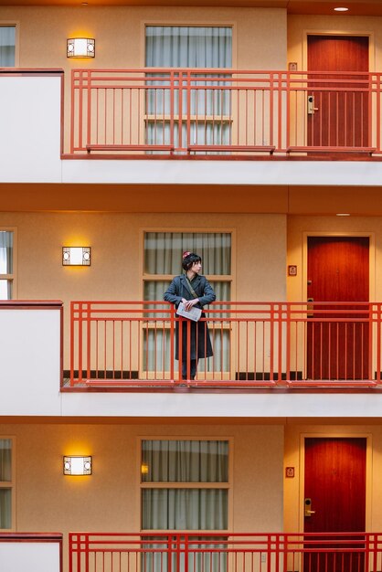Foto una donna si trova su un balcone in una stanza d'albergo.