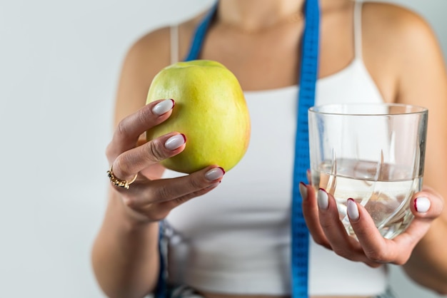 여자는 체중 감량을 위해 사과나 물을 선택하기 전에 서 있다