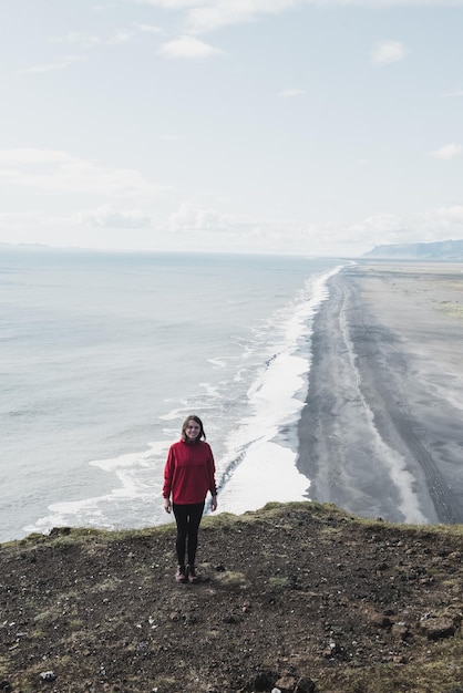 女性はアイスランドの崖の上に立っています
