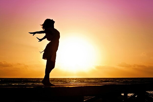 Photo a woman stands on a dock with the sun behind her