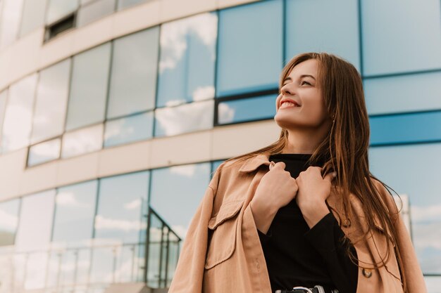 A woman stands in front of a building with a blue sky behind her