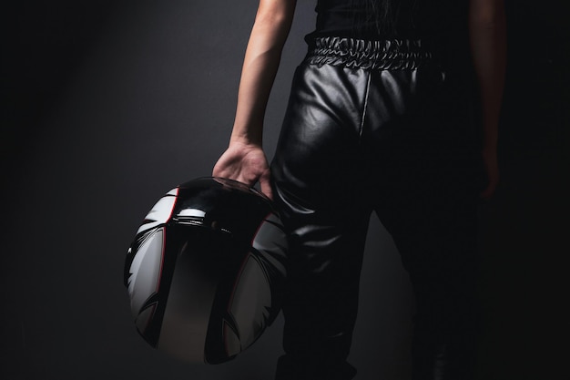 Woman stands holding helmet from motorcycle