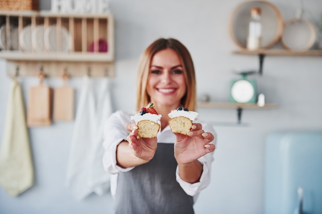 Woman stands indoors in the kitchen with homemade pie.