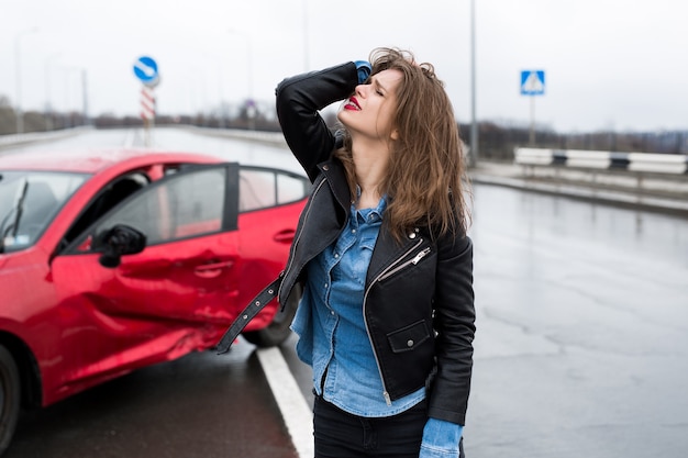 Woman stands near a broken car after an accident. call for help. car insurance