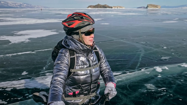 写真 女性は氷の上で自転車の近くに立っている女の子のサイクリストはrに立ち寄った