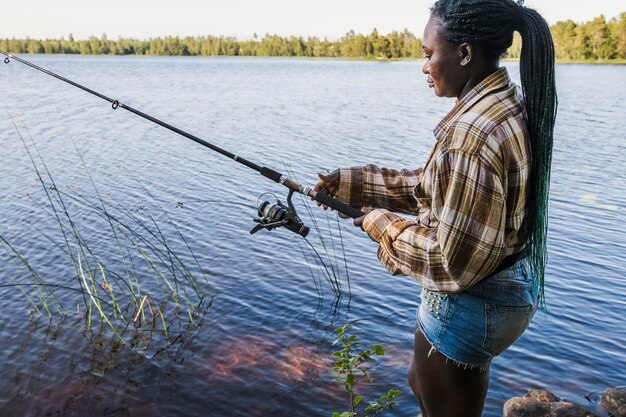 Woman stands and reels in the fishing line during a fishing trip