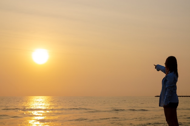 Woman stands at the sunset over the sea and the colorful sky