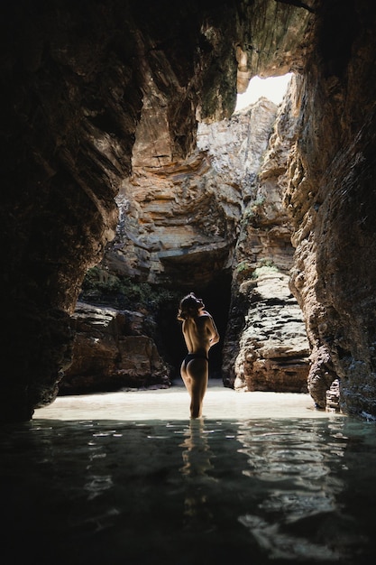 A woman stands in the water in a cave.