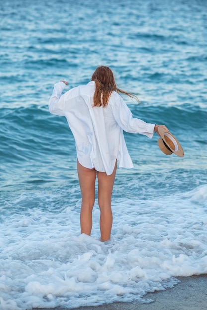 Foto una donna si trova nell'acqua con una camicia bianca e jeans.