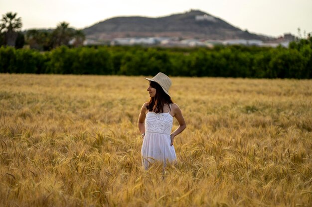 山の前の麦畑に立つ女性