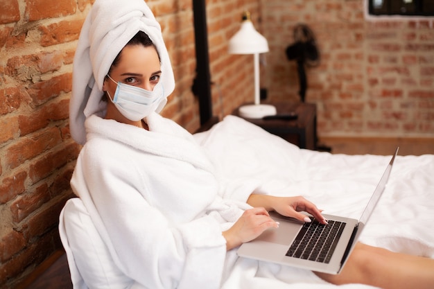 Женщина остается дома во время эпидемии и работает на ноутбуке
